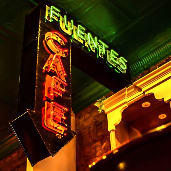 Neon sign for "Fuentes Cafe" with green and red lights pointing downwards.