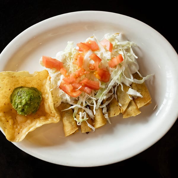 Fuentes Cafe Downtown's taquitos topped with shredded cabbage, diced tomatoes, and a side of guacamole.