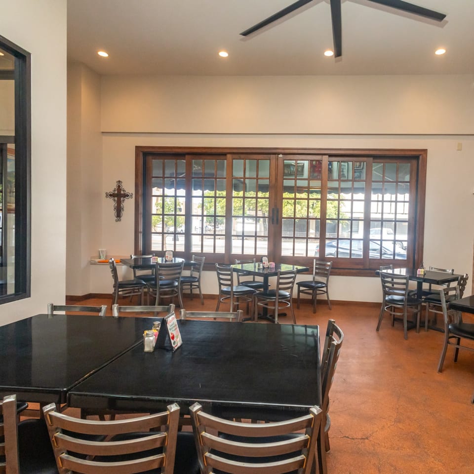 Interior of Fuentes Cafe Downtown, showing empty tables and chairs, with large windows overlooking a street.