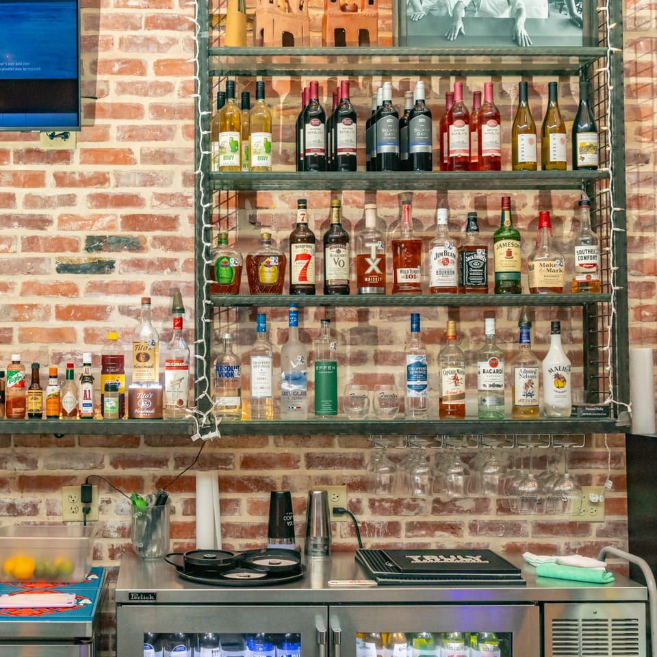 A well-stocked bar at Fuentes Cafe Downtown with various liquor bottles, glasses, and bar equipment.