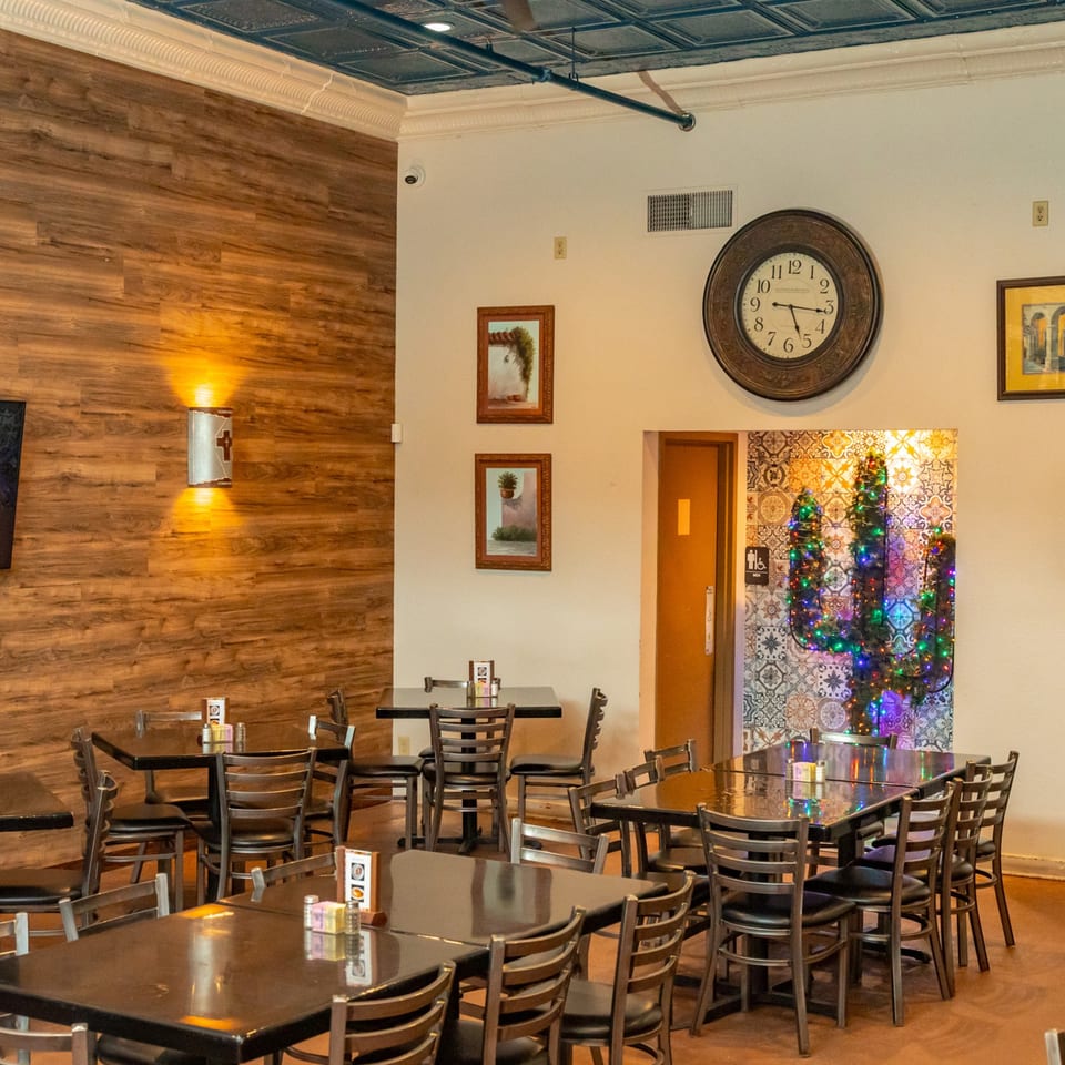 Interior of Fuentes Cafe Downtown with tables, chairs, wood paneling, and a decorative lit cactus.
