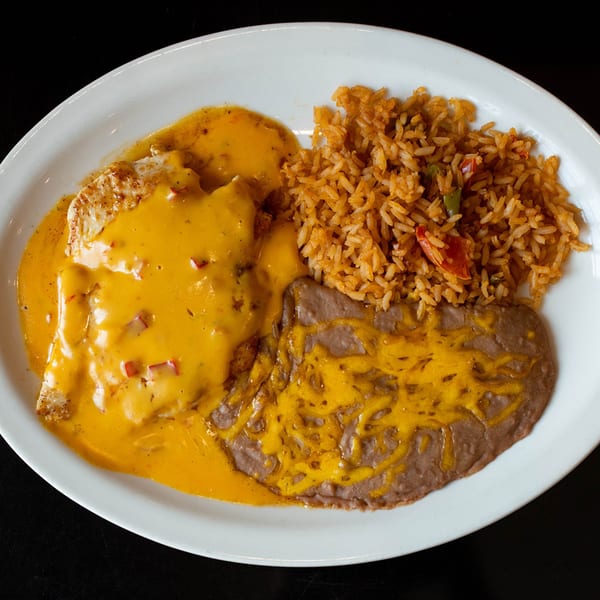 Chicken covered in queso, served with Mexican rice and refried beans with melted cheese.